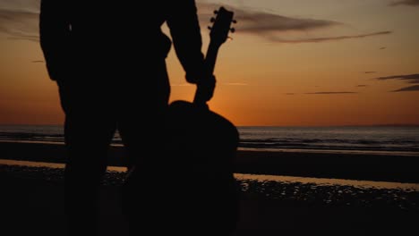 Man-running-with-guitar-in-back-sand-beach-at-sunset-28
