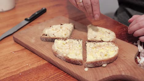 Woman's-hands-with-salt-cut-two-slices-of-bread-smeared-with-butter-and-garlic