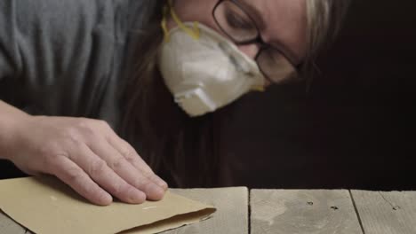 Woman-sanding-wood-while-wearing-protective-dusk-mask