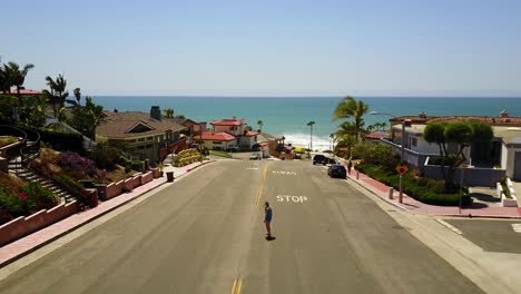A-girl-riding-a-skateboard-down-a-small-hill-near-a-Southern-Californian-Beach