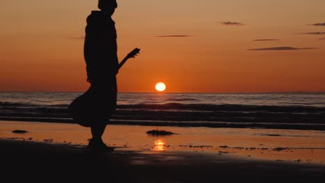 Man-running-with-guitar-in-back-sand-beach-at-sunset-7