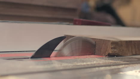 A-piece-of-wood-is-cut-in-two-on-a-table-saw-in-slow-motion-close-up
