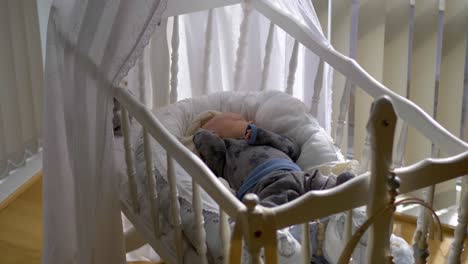 Sleeping-baby-boy-lying-on-cot