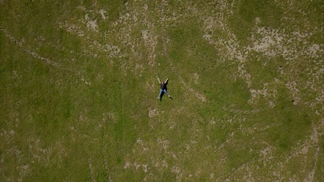 Toma-Aérea-De-Drones-Volando-Sobre-La-Mujer-Adulta-Con-Una-Camiseta-Negra-Sobre-La-Hierba-Verde-En-El-Parque