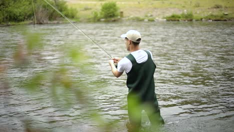 Slow-Motion-Shot-of-a-Caucasian-male-fisherman-casting-his-hook-while-Fly-Fishing-3