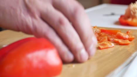 Close-up,-shallow-focus-on-male-hands-in-home-kitchen-slicing-fresh-red-bell-peppers-ingredients-for-colourful-nutritious-meal