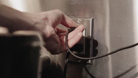 Pulling-Out-The-Electrical-Cord-From-The-Outlet-To-Unplug-The-Appliance---Close-Up-Shot