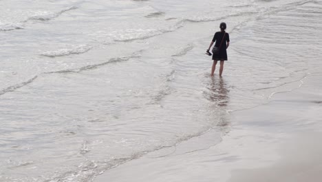 Woman-walking-along-the-shore-of-the-beach
