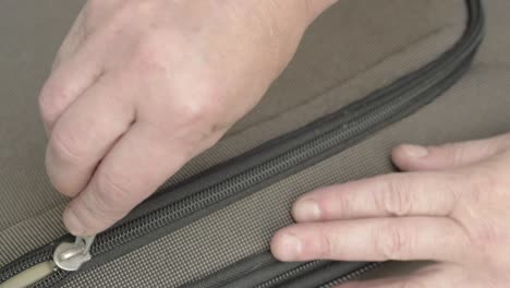 Hand-pulling-metal-zip--to-open-suitcase-luggage