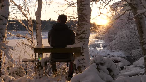 Hiking-man-watching-sunset-in-winter-landscape