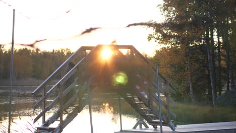 Junger-Wanderjunge,-Der-Auf-Einer-Niedlichen-Holzbrücke-In-Herbstfarbener-Landschaft-Spaziert,-Bei-Goldenem-Sonnenuntergang,-Bereit-Für-Die-Einstufung