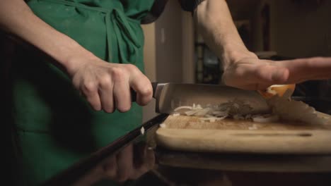 Chefs-Hand-Chopping-White-Onions-Into-A-Wooden-Board-On-Top-Of-A-Table