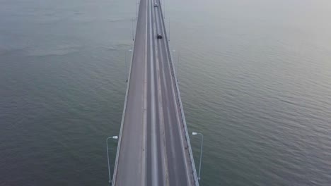 Aerial-tilt,-top-down-view-of-Cars-going-over-massive-grand-bridge-in-seascape
