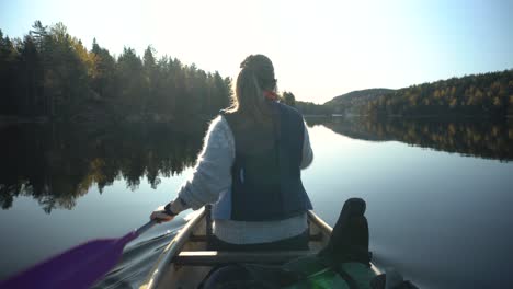 Woman-canoeing-on-beautiful-lake-in-autumn,-back-view
