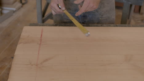 Lumber-is-measured-with-a-tape-measure-in-a-wood-shop-by-a-craftsman