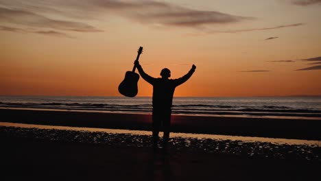 Man-running-with-guitar-in-back-sand-beach-at-sunset-9