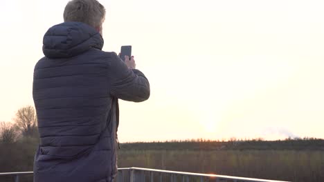 A-person-is-taking-photos-with-his-phone-while-standing-on-a-viewing-platform