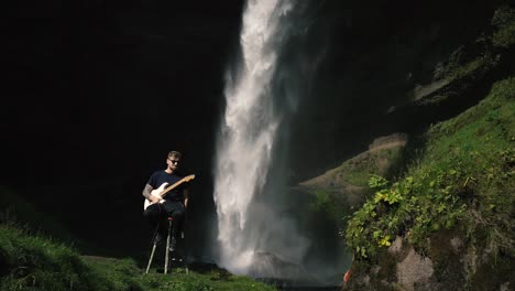 Man-playing-guitar-in-front-of-a-beautiful-waterfall-in-Iceland-14
