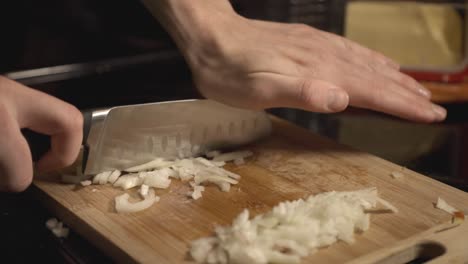 Chefs-Hand-Mincing-A-White-Onions-On-A-Wooden-Cutting-Board