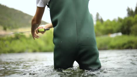 Slow-Motion-Shot-of-a-male-fisherman-wearing-waders-while-Fly-Fishing-1