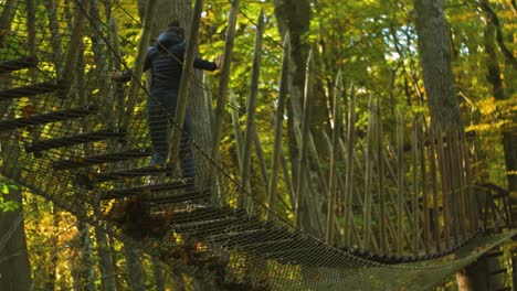 Girl-climbs-over-the-rope-bridge-in-sunny-autumn-day