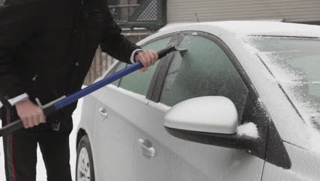 Man-Wearing-Black-Jacket-Removing-Ice-On-His-Car-Window-During-Winter-Day---Closeup-Shot