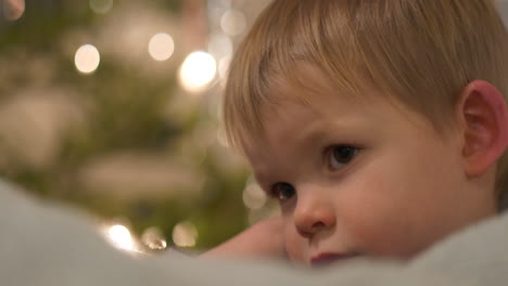 Tired-toddler-during-Christmas,-Christmas-Tree-background,-Close-up
