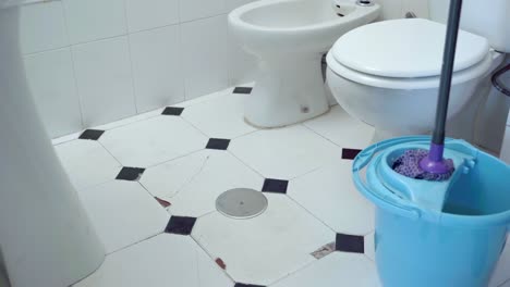Medium-shot-of-mop-squeezing-inside-bucket-with-wringer-inside-restroom