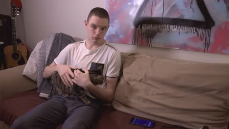 Young-Man-Sitting-On-An-The-Sofa-And-Playing-With-His-Adorable-Cat