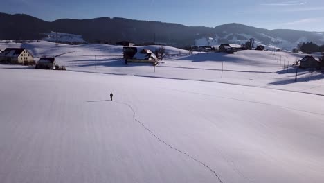 Young-man-walks-in-a-huge-snowy-field-and-stops-and-looks-around-in-Switzerland-while-winter