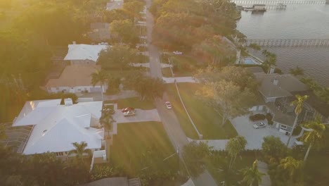 Aerial-View-of-Red-Sports-Car-Driving-Through-South-Florida-Street-at-Sunset-With-River-on-Right