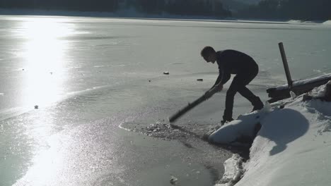 A-Man-Breaking-The-Hard-Ice-In-The-Lake-During-Summer-Weather