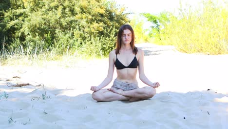 Mujer-Joven-Sentada-En-Una-Posición-De-Loto-En-Una-Playa,-Meditando-En-La-Sombra