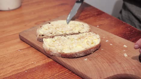 Woman's-hands-puts-garlic-on-two-slices-of-bread-smeared-with-butter