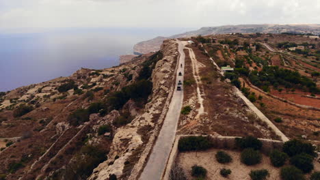 Adventurous-Tourists-Riding-ATV's-Along-Coastal-Road,-Stunning-Gozo-Landscape