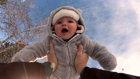 POV-Slo-Mo-shot-of-a-cute-happy-child-in-a-warm-fuzzy-coat,-being-lifted-up-in-the-air