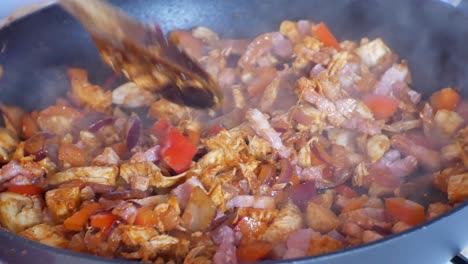 Close-up-on-hands-stirring-hot-steaming-pan-filled-with-healthy-chicken,-peppers---mushrooms-ingredients-for-delicious-meal