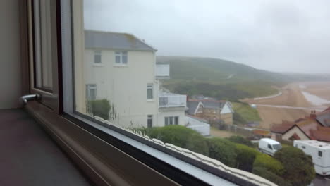 Rain-Flowing-Down-a-Window-with-a-Beach-Visible-in-the-Background-in-Slow-Motion