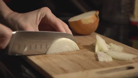 Chef's-Hand-Cutting-Onion-On-A-Wooden-Board