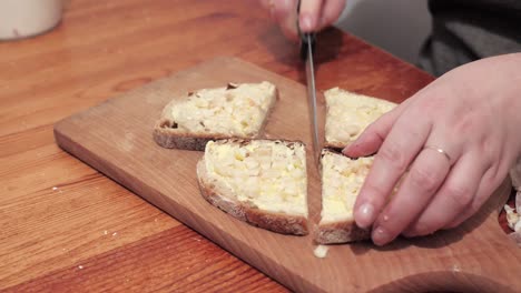 Woman's-hands-cut-two-slices-of-bread-with-butter-and-garlic