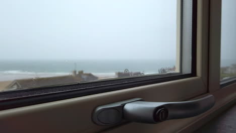Nahaufnahme-Des-Regens,-Der-Ein-Fenster-Hinunterfließt,-Mit-Dem-Ozean-Im-Hintergrund