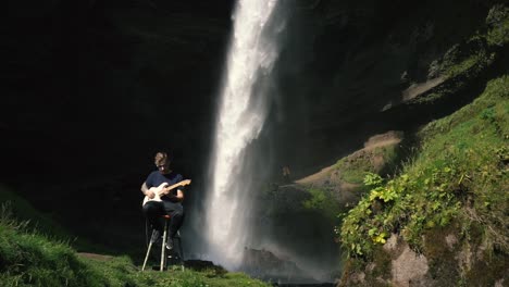Mann-Spielt-Gitarre-Vor-Einem-Wunderschönen-Wasserfall-In-Island-20