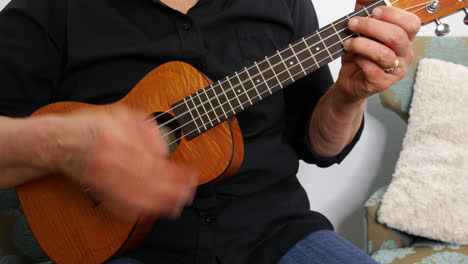 Low-down-view-of-woman-playing-a-ukulele,-pull-away,-handheld