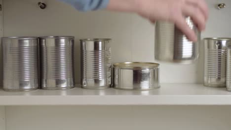 Stacking-aluminum-tin-cans-in-a-food-cupboard-shelf