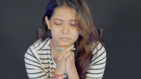Asian-girl-sitting-on-chair,cries-and-prays-for-dead-person