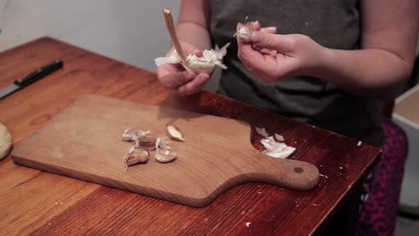 Woman's-hands-peeling-garlic-on-a-chopping-board-1