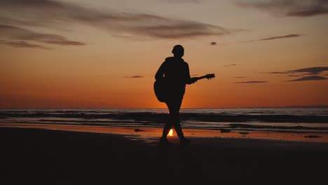 Man-running-with-guitar-in-back-sand-beach-at-sunset-10