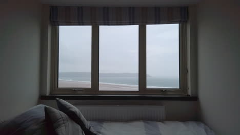 Raindrops-Falling-against-a-Window-in-Slow-Motion-with-an-Ocean-View-and-a-Single-Bed-in-the-Foreground