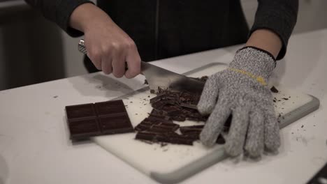 A-young-girl-cuts-up-dark-chocolate-before-melting-it-for-millionaire-shortbread-cookies-while-wearing-safety-gloves-2
