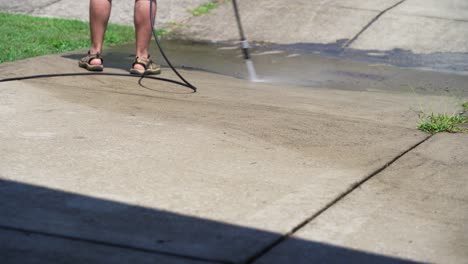 Man-pressure-washing-dirty-concrete-in-the-heat